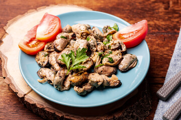Peeled mussels in sauce on a dark wooden background.