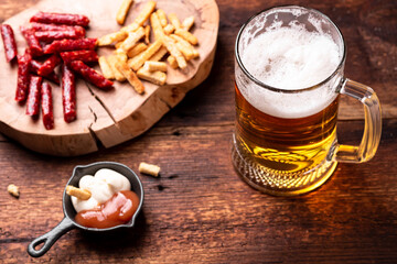 Glass of beer and snacks on a wooden background.