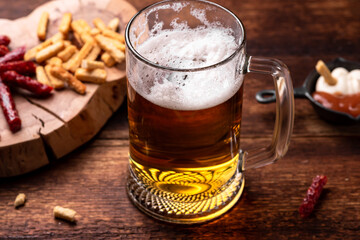 Glass of beer and snacks on a wooden background.