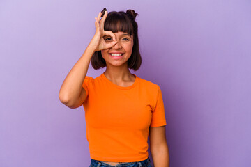 Young mixed race woman isolated on purple background excited keeping ok gesture on eye.