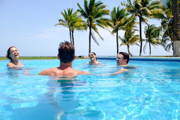 A happy and young group of friends having a fun time in the swimming pool by the beach