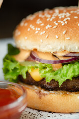 Close-up of tasty burger with salad cheese and sauce, fried potatoes and kethcup