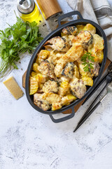Baked mackerel with potatoes and cheese on a marble tabletop.