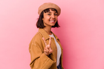 Young mixed race woman isolated on pink background showing victory sign and smiling broadly.