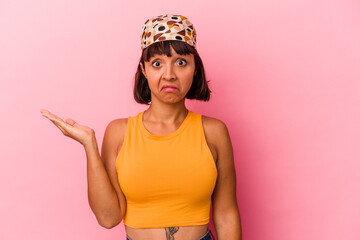 Young mixed race woman isolated on pink background doubting and shrugging shoulders in questioning gesture.