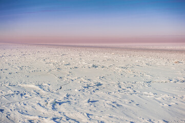 Winter landscape with frozen ice field with fairway and sky.