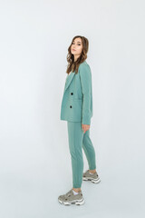 a woman in a green suit with a top and sneakers on a white background. trending women's fashion 2021.