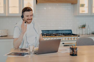 Happy young man having lesson during elearning on laptop at home