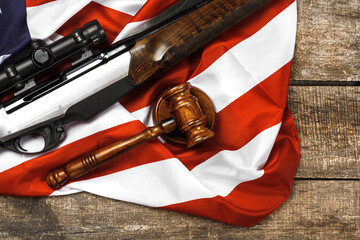 Wooden judge gavel and hunting rifle over USA flag on wooden background