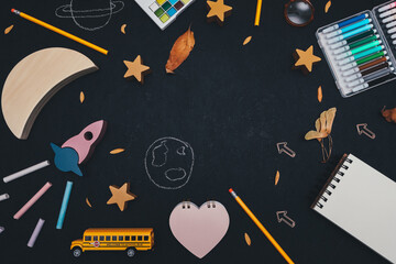 School supplies on black.
Rocket, moon, stars, school bus and supplies on a black background with space for text in the middle, close-up top view.
