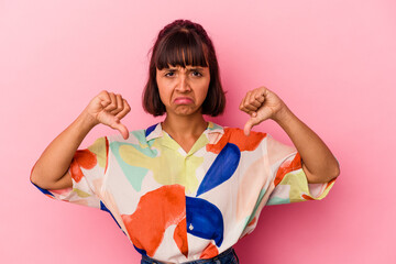 Young mixed race woman isolated on pink background showing a dislike gesture, thumbs down....