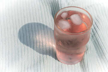Glass of pink lemonade with ice. Soft green cloth background. No straw.
