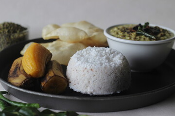 Steamed rice cake served with steamed plantain, green gram curry and papad. A favorite dish of Kerala commonly known as puttu with payar and pappadam.
