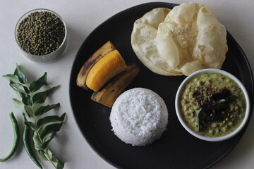 Steamed rice cake served with steamed plantain, green gram curry and papad. A favorite dish of...