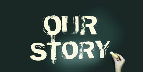 Our story words in pale yellow on blackboard and hand with chalk. Personal branding concept....