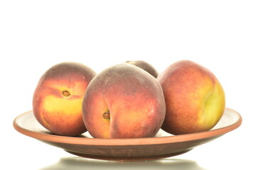 Several ripe organic peaches on a clay plate, close-up, isolated on white.