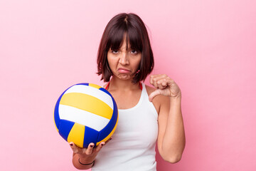 Young mixed race woman playing volleyball isolated on pink background showing a dislike gesture, thumbs down. Disagreement concept.