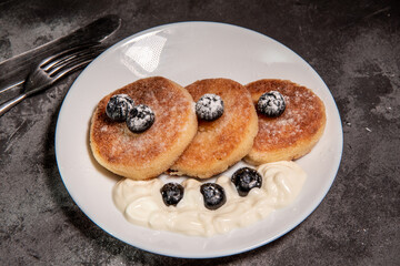 Cottage cheese pancakes with blueberries on a white plate with a knife and fork. Healthy breakfast