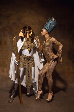 Young woman in image of Nefertiti in art performance isolated on brown vintage background. Retro style, comparison of eras concept.