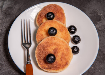 Cheesecakes (curd pancakes) with blueberries on a white plate. Healthy tasty breakfast. Close-up