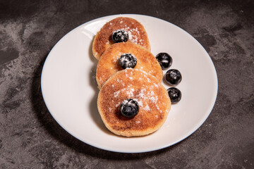 Cheesecakes (curd pancakes) with blueberries on a white plate. Healthy tasty breakfast. Close-up