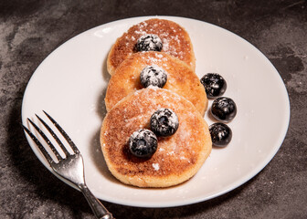 Cheesecakes (curd pancakes) with blueberries on a white plate. Healthy tasty breakfast. Close-up