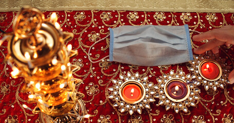 Lit candles and face mask on red ornamental clothing