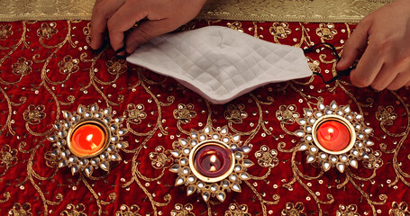Hands on the headdress next to the burning ornamental candles on red clothing