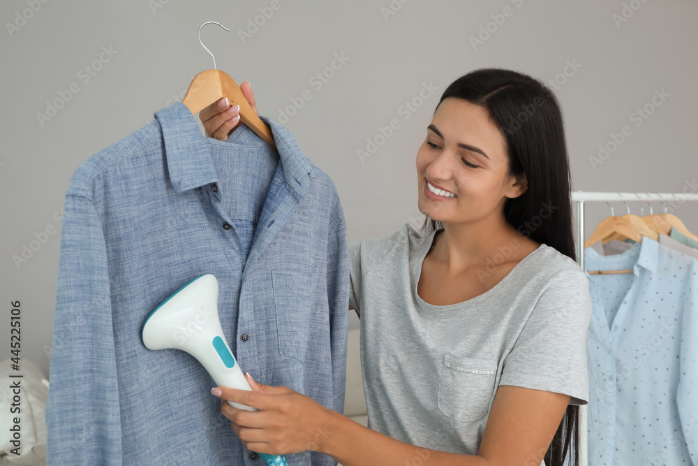 Wall mural Woman steaming shirt on hanger at home