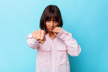 Young mixed race woman isolated on blue background throwing a punch, anger, fighting due to an argument, boxing.