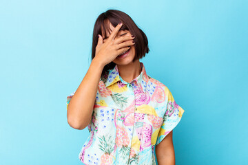 Young mixed race woman isolated on blue background covers eyes with hands, smiles broadly waiting for a surprise.