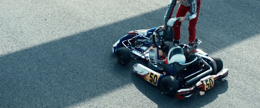 Teenager professional karting racer closing visor and starting his kart on a racetrack. Shot with 2x anamorphic lens