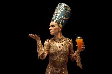 Portrait of young woman in image of Nefertiti in art performance isolated on dark background. Retro style, comparison of eras, humor concept.