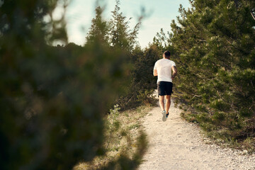 Young muscular male athlete running up the hill