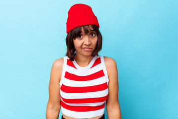Young mixed race woman isolated on blue background shrugs shoulders and open eyes confused.