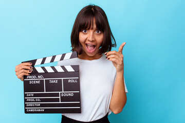 Young mixed race woman holding a clapper board having an idea, inspiration concept.