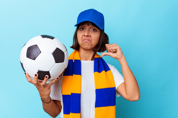 Young mixed race woman watching soccer isolated on blue background feels proud and self confident,...