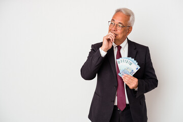 Senior american business man holding bills isolated on white background relaxed thinking about something looking at a copy space.