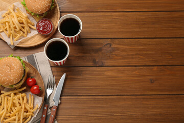 Flat lay composition with delicious fast food menu on wooden table. Space for text