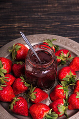 Jar of strawberry jam on metal copper tray