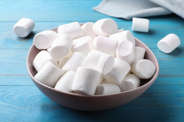 Fototapeta na wymiar Delicious puffy marshmallows on light blue wooden table, closeup