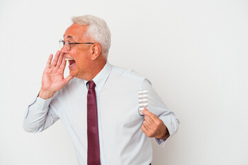 Senior american man holding pills isolated on white background shouting and holding palm near opened mouth.