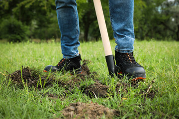 Worker digging soil with shovel outdoors, closeup