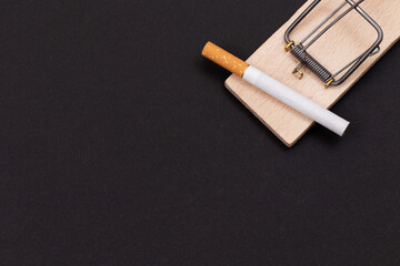 Tobacco Addiction and the World Corporation's Trap - Cigarettes in Wooden Mousetrap on Black Background