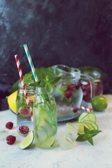 A variety of refreshing detox drinks made from organic fruits, ice, raspberries, cucumbers, lime and mint leaves, on the kitchen table, summer, healthy food, slimming water