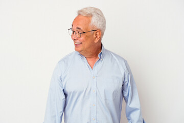 Senior american man isolated on white background looks aside smiling, cheerful and pleasant.