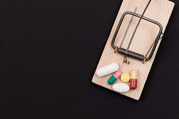Pharmaceutical Addiction or Big Pharma Trap - Colored Pills or Capsules in Wooden Mousetrap on...