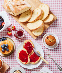 BIG BREAKFAST WITH BREAD AND JAM ON A RED SQUATE TABLECLOTH