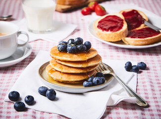 blueberry pancake with marple syrup ON A RED SQUATE TABLECLOTH