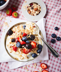 yogurt with berries and granola ON A RED SQUATE TABLECLOTH
